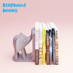 an elephant bookend sitting next to a stack of books on top of a pink background