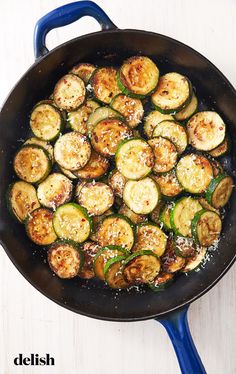 cooked zucchini and peppers in a skillet on a white wooden table top