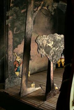 an elephant statue is standing in front of two mirrors on a wooden floor with people looking at it