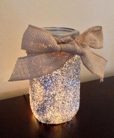 a glass jar with a bow on it sitting on a table next to a wall