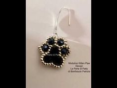 a pair of black and silver earrings with paw prints on them, hanging from hooks