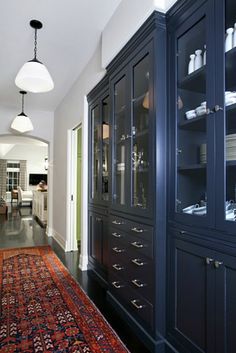 a large rug is in the middle of a room with blue cabinetry and white walls