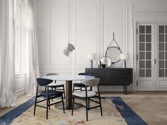 a dining room with white walls and blue chairs around a round table in front of a mirror