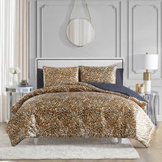 a leopard print comforter set on a bed in a room with white walls and flooring