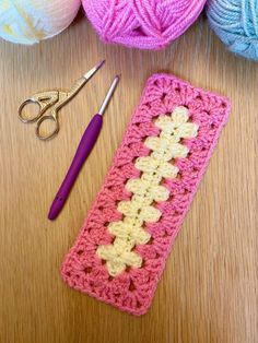 a crochet bookmark next to some yarn and a pair of scissors on a table