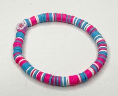 a pink, blue and white beaded bracelet with a flower on the end of it