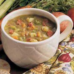 a white bowl filled with soup sitting on top of a table next to some vegetables