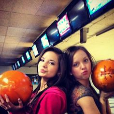 two women holding bowling balls in their hands