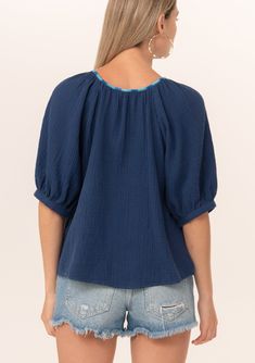 A navy blue bohemian puff sleeve blouse designed in soft cotton gauze. Cotton gauze Relaxed fit Short raglan puff sleeve Round neckline with contrast thread detail Button front Bohemian summer blouse A contrast thread detail adds a unique charm to this classic bohemian blouse. Designed in soft cotton gauze, featuring raglan puff sleeves, a flattering scooped neckline, and a button front. Model is 5'9, wearing a size S.Style: I-15055W-RJZ Casual Puff Sleeve Top With Bishop Sleeves For Summer, Blue Summer Top With Elastic Sleeves, Navy Short Sleeve Blouse For Summer, Bohemian Summer Tops With Elastic Sleeves, Bohemian Tops With Elastic Sleeves For Summer, Blue Top With Gathered Short Sleeves, Blue Summer Blouse With Elastic Sleeves, Summer Blue Blouse With Elastic Sleeves, Summer Cotton Blouse With Bishop Sleeves