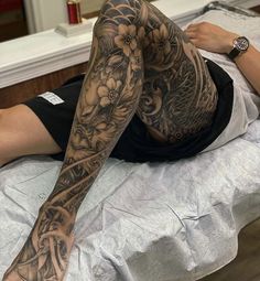 a woman laying on top of a bed with tattoos on her arm and leg,