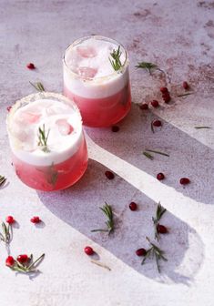 two glasses filled with drinks and garnished with rosemary sprigs on the table