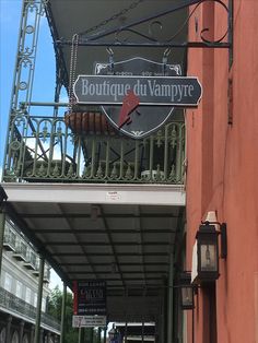 a street sign hanging from the side of a red building next to a sidewalk with people walking on it