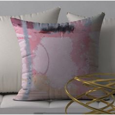 two pillows sitting on top of a white couch next to a gold table and lamp