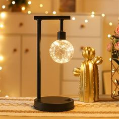 a gold figurine is next to a glass ball on a black stand with lights in the background