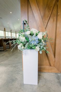 a tall white vase filled with blue and white flowers