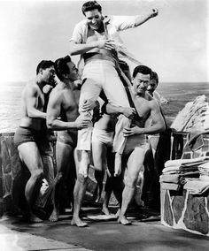 an old black and white photo of men in bathing suits on the deck of a ship