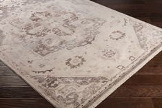 a beige and brown area rug on top of a wooden floor with dark wood floors