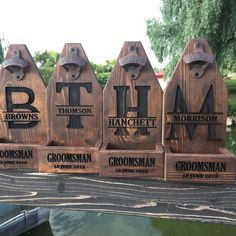 four wooden signs with the names of different towns and cities are displayed in front of a body of water