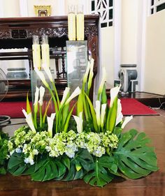 flowers and greenery are arranged on a table