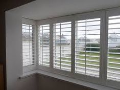 an empty room with white shutters on the windows