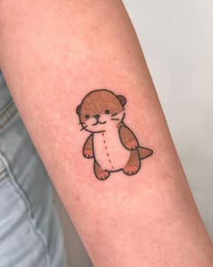 a small otter tattoo on the right forearm and arm, it's brown with an orange outline