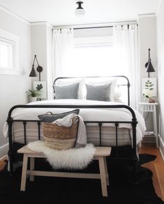 a bedroom with white walls and black metal bed frame in the corner, along with a bench