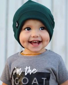 a young boy wearing a green beanie smiles at the camera