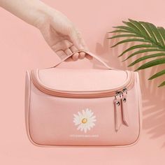 a pink bag with a white flower on the side and a person's hand holding it