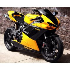 a yellow and black motorcycle parked in front of a brick wall