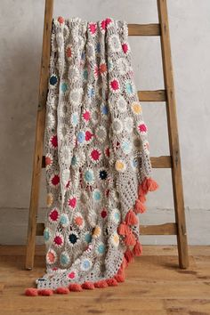 a ladder leaning against a wall with a crocheted blanket on top of it