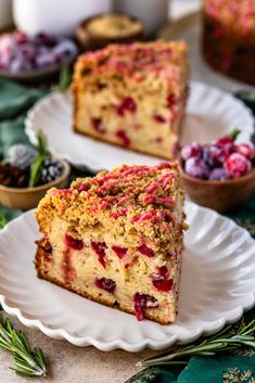 two slices of cranberry coffee cake on white plates with fresh berries in the background