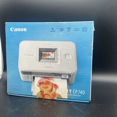 a canon printer sitting on top of a table next to a box with the lid open