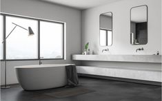 a white bath tub sitting in a bathroom next to two sinks and large mirrors on the wall