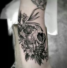 a skull and flowers tattoo on the arm