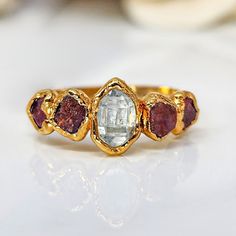 a gold ring with three different colored stones on it's sides and one stone in the middle