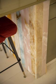 a red chair sitting in front of a tall piece of paper on top of a table