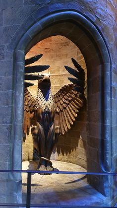 a statue of a bird sitting on top of a stone wall next to a doorway