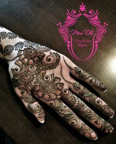 henna tattoo on the palm of someone's hand with pink and black designs