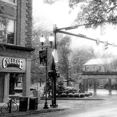 an old black and white photo of a street corner with a college sign on it