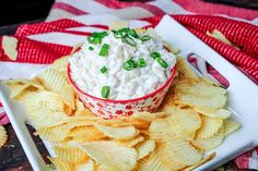 a bowl of dip surrounded by chips on a plate