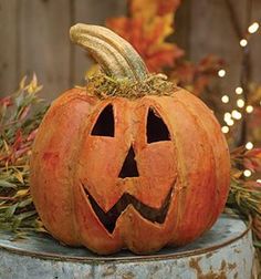 a carved pumpkin sitting on top of a metal barrel