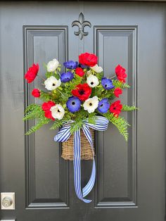 a wreath with red, white and blue flowers on the front door