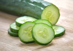 four cucumbers are arranged on a wooden surface