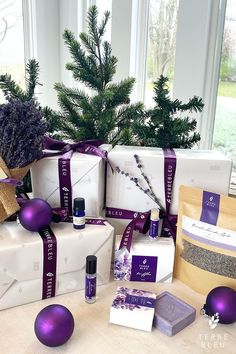 the presents are wrapped in purple ribbon and sitting on the table next to the christmas tree