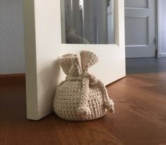 a crocheted bag sitting on the floor in front of a door with a mirror behind it