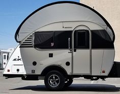 an rv parked in a parking lot with its awning down and the door open