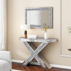 a white couch sitting next to a table with a vase on it and a mirror