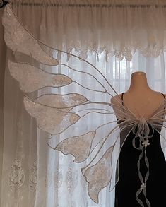 a mannequin is standing in front of a window with white curtains and laces