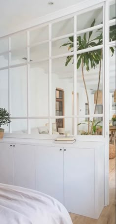 a bedroom with white furniture and plants in the window sill, along with a bed