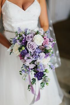 a bride holding a purple and white bouquet